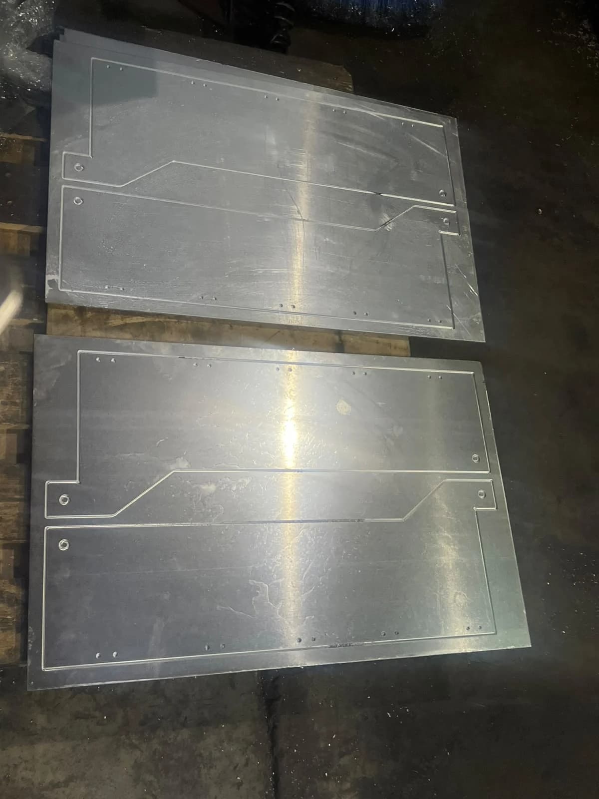 Dos planchas con contornos y perforaciones sobre una superficie de trabajo